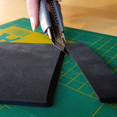 cuttermesser schneidet schräg durch schwarzen foam
